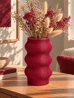 Vase ondulé bordeaux imprimé en 3D, aux courbes sculpturales, posé sur un meuble – Luciole