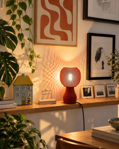 Lampe à poser terracotta ajourée allumée avec son ampoule LED sur un meuble en bois